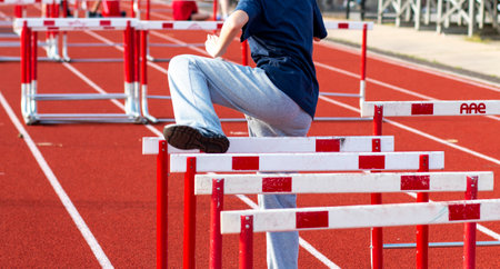 Rear view of one high school girl performing hurdle drills warming up for a race outdoors.の写真素材