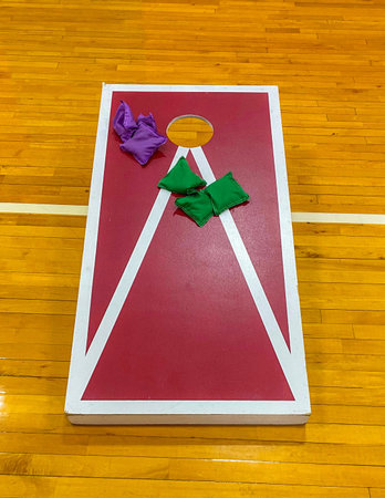 Corn hole game with colorful bean bags inside on a gym floor being used for high school gym class.の写真素材