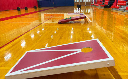 Side view of homeade Cornhole game boards and bowling set up in a gymnasium for gym class.