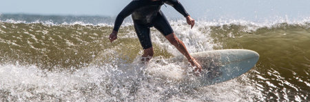 Front view of a man surfing and splashing in rough waves at Gilgo Beach on long Island Close up.