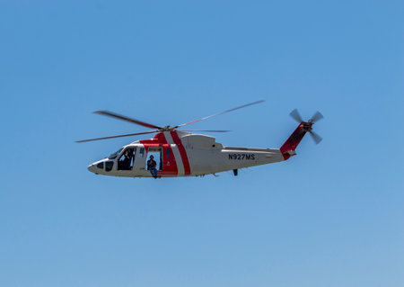 Coaco Beach Florida, USA - 27 June 2023: A rCoast Guard ed and white helicopter flying through a blue sky over the Atlantic Ocean in Florida.のeditorial素材