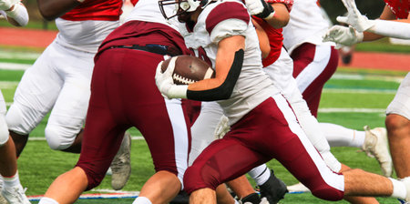 American football player running with the ball behind his blockers during a gameの写真素材