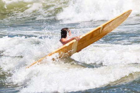 Female Surfer getting hit by waves trying to get into the Atlantic Ocean to go surfing.