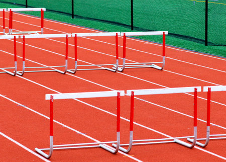 Many Hurdles set up in lanes on a red track for an outdoor race.の写真素材