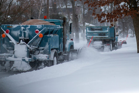 Two snowplows working bakc to back clearing snow and dropping sand at the end of a blizzard in...