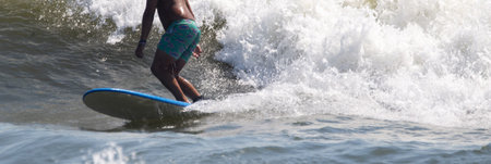 Close up of a male surfer iin a bathing suit surfig on a wave at Giglo Beach off the coast of Long...