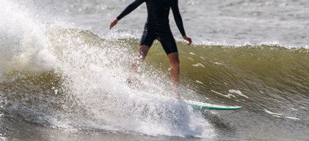 Close up of a Man surfing on a rough wave wearing a black short wetsuit at Gilgo Beach of Long Island New York.の写真素材