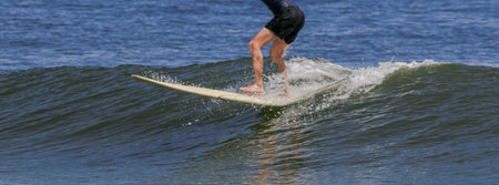 Surfers legs riding on top of a wave while surfing at Gilgo Beach on Long Island.の写真素材