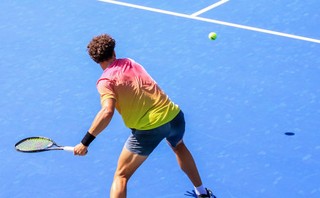 Rear view of a male tennis player swinging aggressively with a strong forehand close up,の写真素材