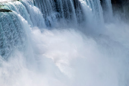 Close up of water flows powerfully over a cliff, creating mist and a breathtaking display of nature's beauty during daytime.の写真素材