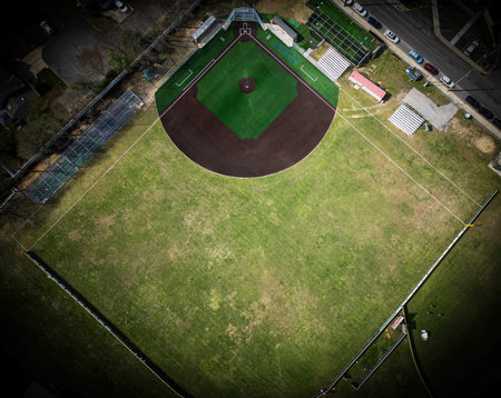 An aerial view captures a new green artificial turf baseball field with a natural grass outfield from 400 feet above and a vignette darkening the outside.の写真素材