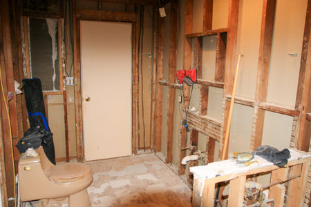 Drywall removal reveals plumbing and electrical work in early renovation stage.の写真素材