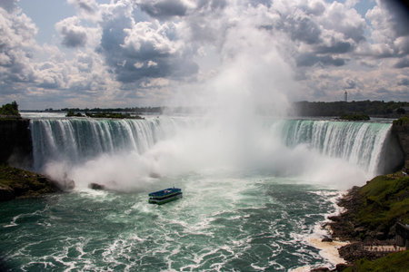Visitors enjoy a boat tour as they experience the beauty of cascading Niagara Falls.の写真素材