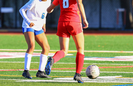 Two young female soccer players compete for the ball on a vibrant turf field.の写真素材