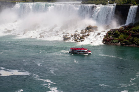 Tourists enjoy a boat ride as they approach the powerful Niagara Falls during summer.の写真素材