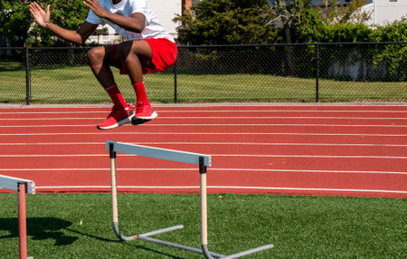 A young athlete practices jumping over hurdles on a sunny day.の写真素材