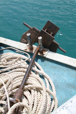 Rustic anchor surrounded by Rope on fishing boatの写真素材