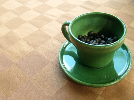 Green coffee cup with coffee beans inside Placed on the leather tableclothの写真素材