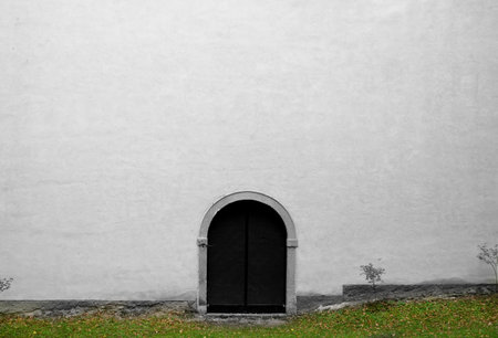 Big white wall with small wooden door. Architecture detail of old churchの写真素材