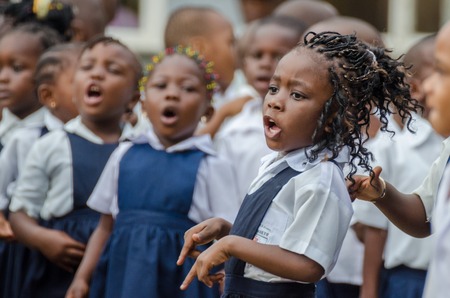 Young African school girl with beautifully decorated hair singing and dancing at pre-school in Matadi, Congo, Africaのeditorial素材
