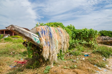 Colorful overgrown and broken wooden fishing boats with nets and traps in lush environment, coast of Gambia, West Africaの写真素材