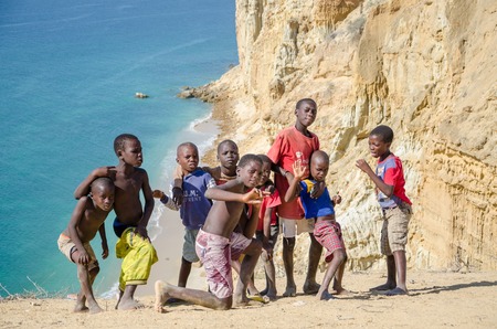 CAOTINHA, BENGUELA, ANGOLA - MAY 11 2014: Group of young African boys posing in front of spectacular desert coast line and ocean at Praia da Caotinha.のeditorial素材