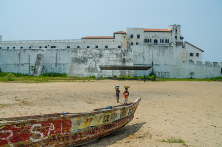 Elmina, Ghana - February 13, 2014: Elmina castle with wooden fishing boat and beach in foregroundのeditorial素材