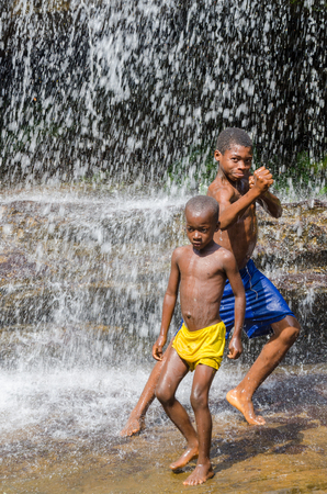 Kindia, Guinea - December 28, 2013: Two unidentified young African boys wplaying and having fun under waterfallのeditorial素材
