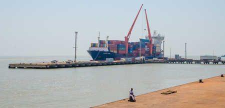 Bissau, Guinea Bissau - December 06, 2013: Container ship unloading at small port of Bissauのeditorial素材