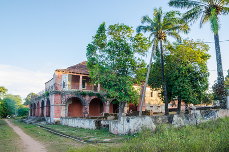 Bubaque, Guinea Bissau - December 11, 2013: Ruined manson and tropical vegetation next to dirt pathのeditorial素材