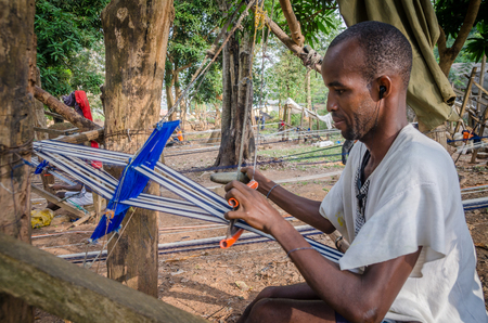Man, Ivory Coast - January 31,2014: Unidentified African man weaving traditional blue and white Yacouba cloth outdoorsのeditorial素材