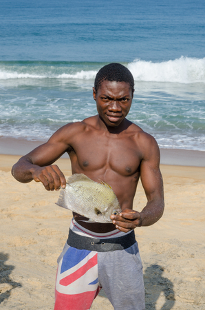 Robertsport, Liberia - January 26, 2014: Portrait of African fisherman presenting catch at beachのeditorial素材