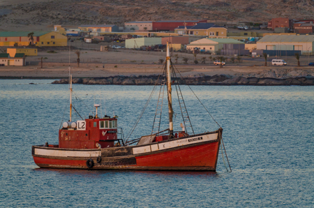 Luderitz, Namibia - July 09 2014: Old red wooden fishing boat in bay at Luderitz during eveningのeditorial素材