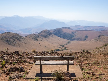 Empty wooden bench overlooking mountains and arid landscape of Malolotja Nature Reserve, Swaziland, Southern Africaの写真素材