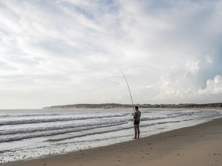 Luanda, Angola - April 26, 2014: Recreational young fisherman standing at beach north of Luanda angling, Angola, Africaのeditorial素材