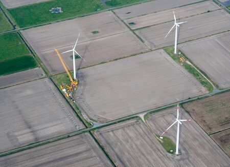 Aerial view of wind turbine or windmill construction with crane on field, Nordfriesland, Germany.の写真素材