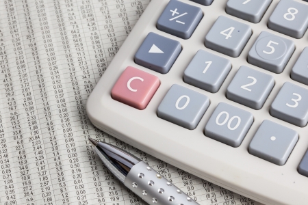 Metal pen and calculator placed on stock data newspaperの写真素材