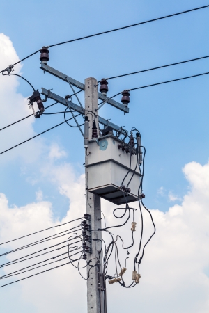 Electric pole against blue sky with white cloudsの写真素材