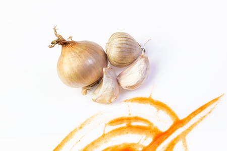 Garlics and onion on chilli sauce pattern on white backgroundの写真素材