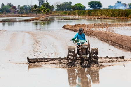 Thai farmer plowing his farm with small tractorの写真素材