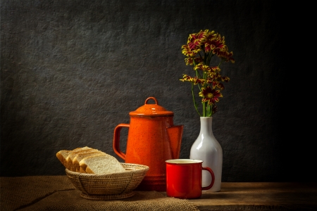Still life with a red cup and tea pot with a basket of breadの写真素材