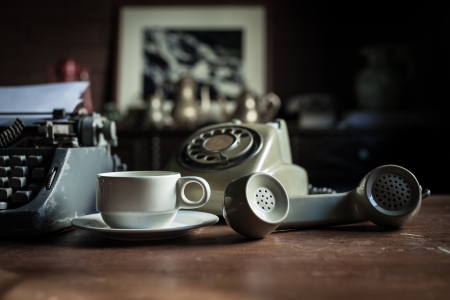 telephone, type writer and flower in silver vase place near old lamp on wooden tableの写真素材