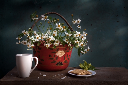 red basket with white flower, coffee cup and biscuits on wooden tableの写真素材