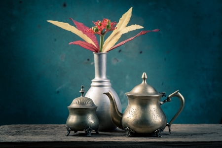 brass tea set and silver vase with colorful flowersの写真素材