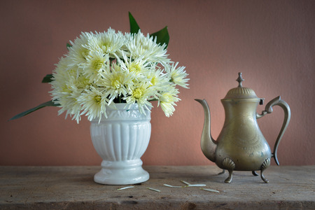 Still life with white dahlias in vase and brass tea pot on wooden tableの写真素材