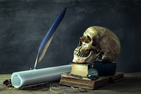 Still life with human skulls and bunch of red onions on wooden tableの写真素材