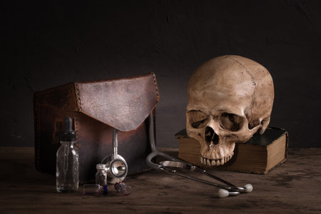 Still life with human skull on old book, stethoscope and pocket watch