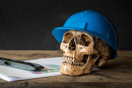 Human skull with blue safety helmet and blueprintの写真素材