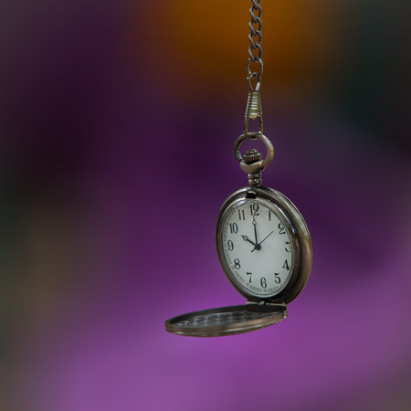 Open pocket watch on colorful soft focus background