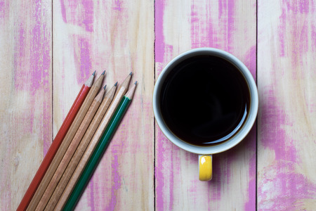 coffee cup and pencils on the pink wooden tableの写真素材